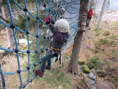 zeigt Kind beim Klettern im Waldkletterpark